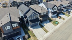 Modern residential architecture featuring a dark gray roof, light gray siding, and a contrasting warm-toned accent panel - 