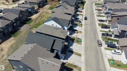 Newly developed residential street featuring modern homes with dark asphalt shingle roofing - 