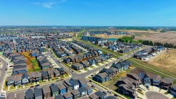 Aerial perspective showcasing a residential community with diverse architectural styles, paved streets, and a clear blue sky - 