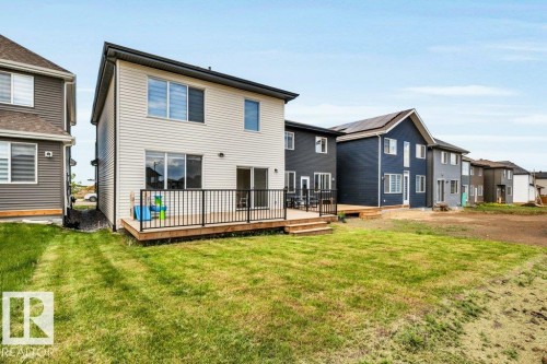 Two-story residence featuring light-colored siding and a rear wood-deck with black metal railing - 13007 213 Street, Edmonton, AB 