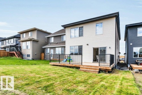 Expansive grassy yard with a multi-level wooden deck featuring black metal railings - 13007 213 Street, Edmonton, AB 