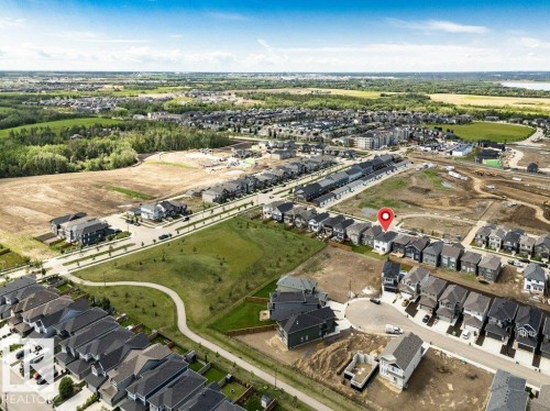 Aerial perspective of a developing residential area featuring multiple housing styles, paved roadways, and green spaces - 13007 213 Street, Edmonton, AB 