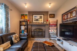 Brick fireplace with a metal screen and a stone hearth, flanked by a built-in bookshelf - 