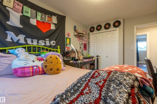 Bedroom featuring a light gray wall color, a white bi-fold closet door, and a wood-finish flooring visible through the doorway - 8902 107 Avenue, Morinville, AB 