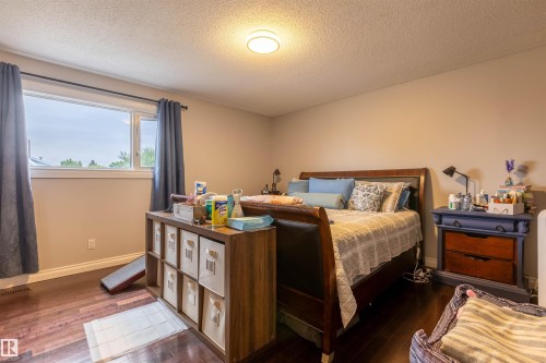 Bedroom featuring wood-finish flooring, a neutral wall color, and a large window with white trim - 8902 107 Avenue, Morinville, AB 