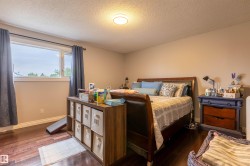 Bedroom featuring wood-finish flooring, a neutral wall color, and a large window with white trim - 