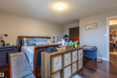 Spacious room featuring rich wood-finish flooring, light neutral wall paint, and a ceiling-mounted light fixture - 8902 107 Avenue, Morinville, AB 
