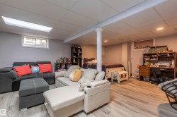 Finished basement space featuring light wood-finish flooring, recessed lighting, drop ceiling, and a prominent support pillar - 