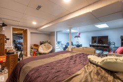 Finished basement area featuring recessed lighting, painted walls, drop ceiling, and a separate room with wood-finish door - 