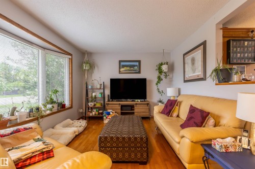 Living area featuring prominent bay windows with wood trim, wood-finish flooring, a built-in wall niche, and light-toned walls - 8902 107 Avenue, Morinville, AB 