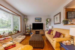 Living area featuring prominent bay windows with wood trim, wood-finish flooring, a built-in wall niche, and light-toned walls - 