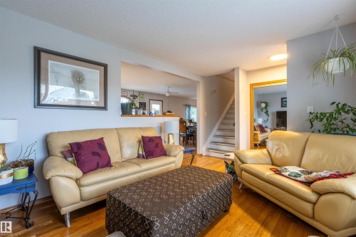 Spacious living area featuring wood-finish flooring, light gray wall paint, and a half-wall architectural detail - 8902 107 Avenue, Morinville, AB 