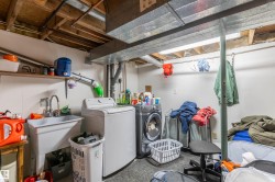 Utility room featuring a laundry sink, exposed wood joists, overhead fluorescent lighting, and a washer and dryer - 