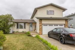 Cream-colored siding exterior featuring a two-car garage with paneling and transom window details - 