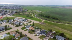 Residential neighborhood bordered by green fields, a winding path, and a water feature - 