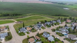 Aerial perspective showcasing a residential area bordered by expansive green fields and a natural water feature - 