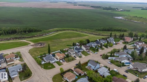 Residential neighborhood featuring an array of single-family homes with diverse architectural styles, paved streets, and a backdrop of expansive green fields - 8902 107 Avenue, Morinville, AB 