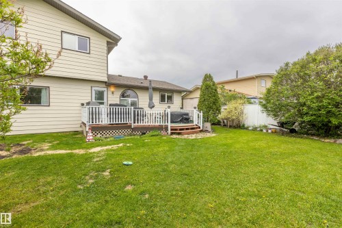Expansive green lawn with a multi-level wood deck featuring white railings - 8902 107 Avenue, Morinville, AB 