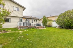 Expansive green lawn with a multi-level wood deck featuring white railings - 