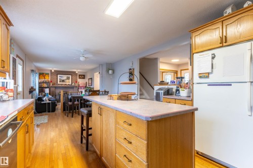 Kitchen featuring wood cabinetry, a central island with storage, and wood-finish flooring - 8902 107 Avenue, Morinville, AB 
