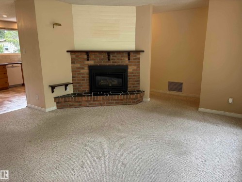 Central brick fireplace with a dark wood mantel and hearth - 51 Glenmore Crescent, St. Albert, AB 