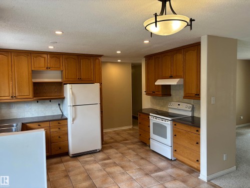 Kitchen featuring wood cabinetry, stone-look countertops, and a tile backsplash - 51 Glenmore Crescent, St. Albert, AB 