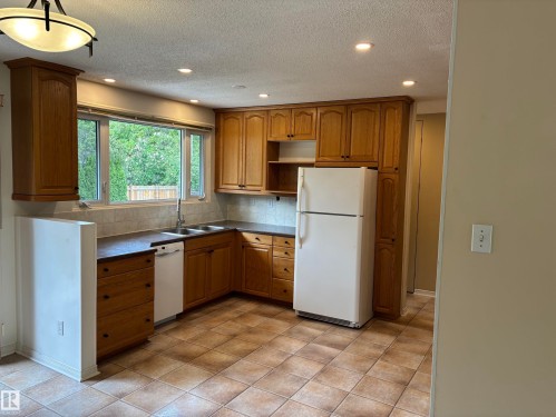 Kitchen featuring wood cabinetry, a double basin sink, tile backsplash, recessed lighting, and tile flooring - 51 Glenmore Crescent, St. Albert, AB 