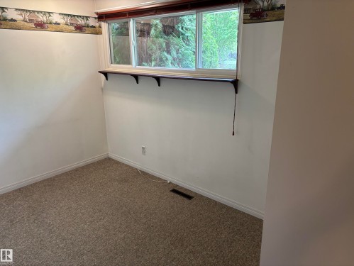 Carpeted room with a wide window, white trim, and a decorative wallpaper border - 51 Glenmore Crescent, St. Albert, AB 