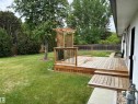Expansive backyard featuring a multi-tiered wood deck with a built-in pergola and black metal balusters - 51 Glenmore Crescent, St. Albert, AB 