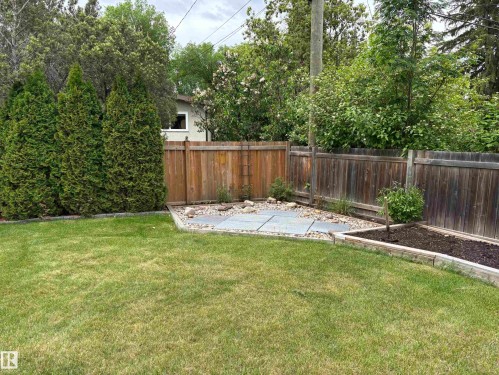 Expansive backyard featuring a lush lawn, a paved patio area, and mature perimeter trees - 51 Glenmore Crescent, St. Albert, AB 