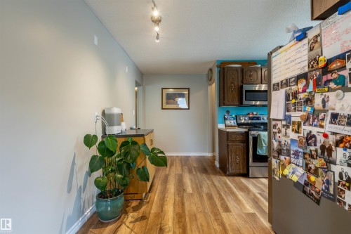 Kitchen area featuring wood-finish flooring, stainless steel appliances, and dark wood cabinetry - 33 Andrew Crescent, St. Albert, AB 