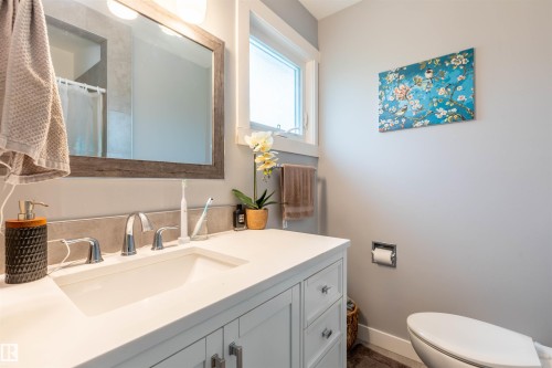 Bathroom vanity featuring a white countertop with an integrated sink, chrome faucet, and white shaker-style cabinetry - 33 Andrew Crescent, St. Albert, AB 