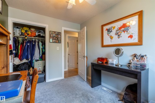 Carpeted room with a ceiling fan, closet with bi-fold doors, white baseboards, and a doorway with a white door - 33 Andrew Crescent, St. Albert, AB 