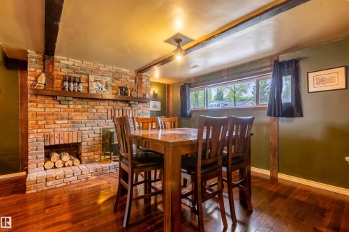 Exposed brick fireplace with a wood mantle, wood-finish flooring, and recessed window - 33 Andrew Crescent, St. Albert, AB 