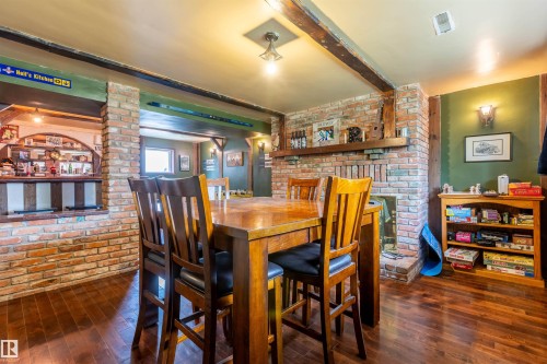 Spacious room featuring wood-finish flooring, exposed brick accents, and a brick fireplace - 33 Andrew Crescent, St. Albert, AB 