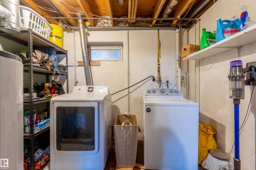 Dedicated laundry area featuring a washer and dryer, exposed ceiling joists, and a small transom window - 33 Andrew Crescent, St. Albert, AB 