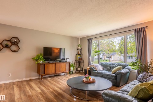 Living area featuring wood-finish flooring, a large picture window, and neutral wall tones - 33 Andrew Crescent, St. Albert, AB 