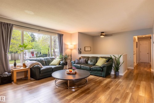 Spacious living area featuring large window, wood-finish flooring, recessed lighting, and a neutral color palette - 33 Andrew Crescent, St. Albert, AB 