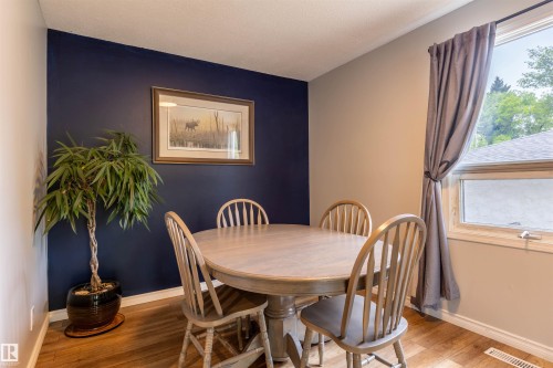 Dining area featuring wood-finish flooring, a window providing natural light, and a contrasting accent wall - 33 Andrew Crescent, St. Albert, AB 