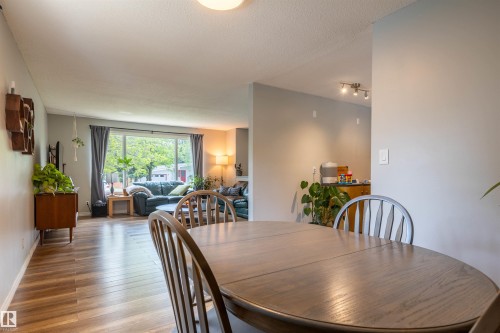 Dining area featuring a wood-finish table, leading to a living room with a large picture window, recessed lighting, and wood-finish flooring - 33 Andrew Crescent, St. Albert, AB 