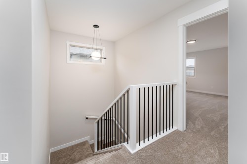 Staircase with modern black metal balusters, white handrail, and carpeted treads - 115 Garneau Gate, Spruce Grove, AB 