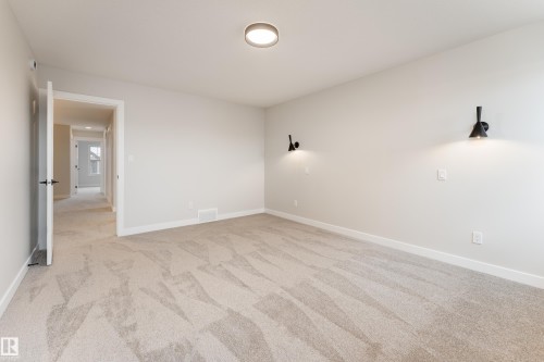 Spacious room featuring neutral carpeting, light-toned walls, and white trim - 115 Garneau Gate, Spruce Grove, AB 