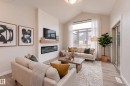 Spacious living area featuring a vaulted ceiling, prominent fireplace with a light-toned wood-finish mantel and a herringbone-patterned surround, and wood-finish flooring - 115 Garneau Gate, Spruce Grove, AB 