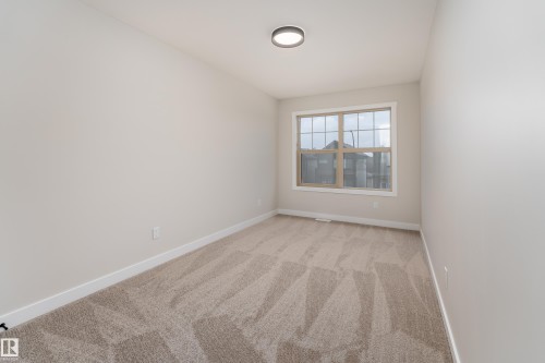 Neutral-toned carpet flooring in a room featuring a multi-pane window and a contemporary ceiling light fixture - 115 Garneau Gate, Spruce Grove, AB 