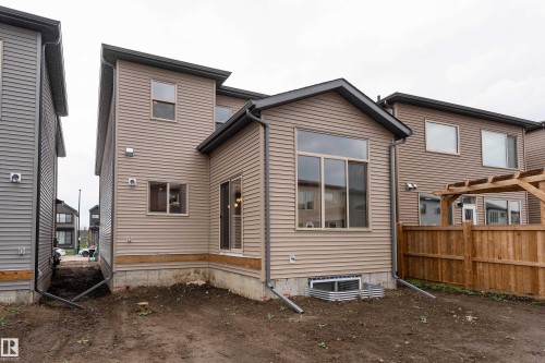 Rear exterior featuring horizontal siding, a large picture window, and an attached wood pergola - 115 Garneau Gate, Spruce Grove, AB 