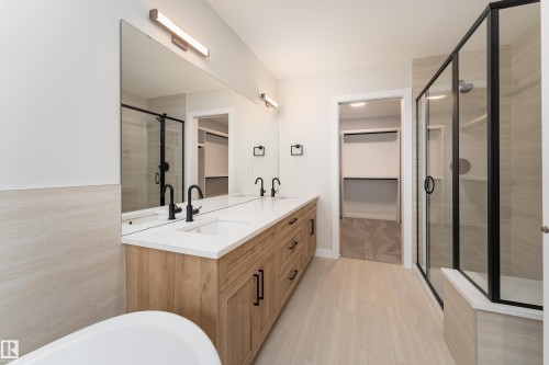 Contemporary bathroom with a light wood-finish double vanity, white countertop, and matte black fixtures - 115 Garneau Gate, Spruce Grove, AB 