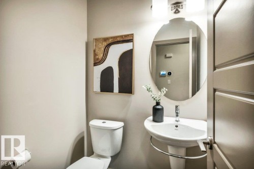 Pedestal sink with chrome faucet, oval mirror, and wall-mounted light fixture - 1107 Chahley Crest, Edmonton, AB 