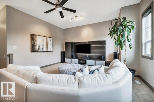 Spacious living area featuring a ceiling fan, recessed lighting, built-in entertainment center, and a large window - 1107 Chahley Crest, Edmonton, AB 
