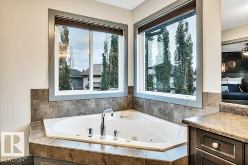 Corner soaking tub with tile surround, dual windows, and built-in vanity with countertop - 1107 Chahley Crest, Edmonton, AB 