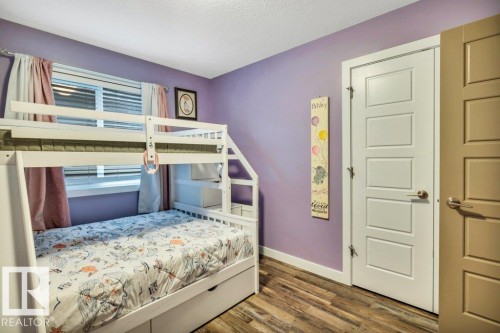 Room featuring wood-finish flooring, a white five-panel door, and a multi-pane window with blinds - 1107 Chahley Crest, Edmonton, AB 